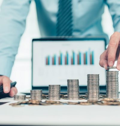 Hand putting money coins stack growing, saving money for finance accounting concept.